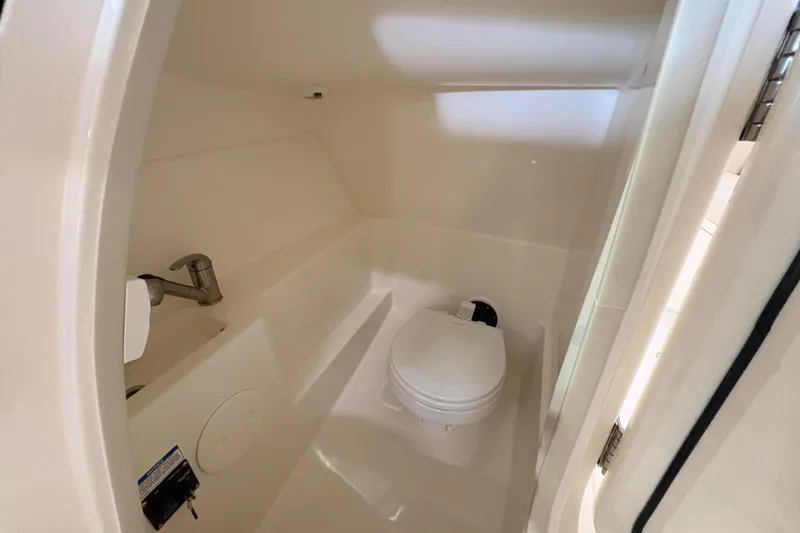 Slide: The Image of Interior of 2026 Boston Whaler 240 Vantage boat, featuring a compact marine toilet. - 14