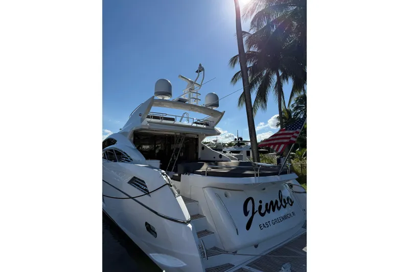 Slide: The Image of 2012 Sunseeker Predator Sport Yacht 74 docked, with palm trees and American flag in background. - 32