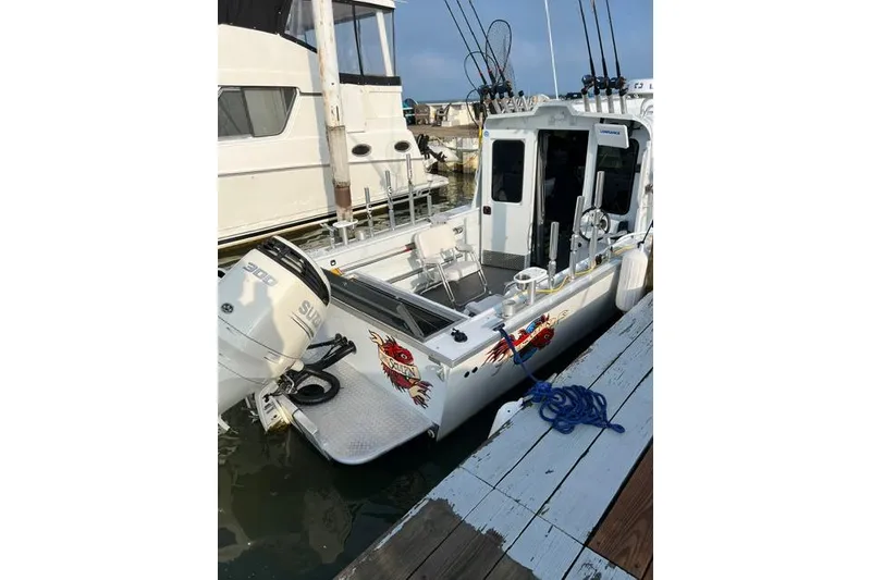 Slide: The Image of 2020 Hewescraft 240 Ocean Pro boat docked, featuring fishing rods and Suzuki outboard motor. - 2