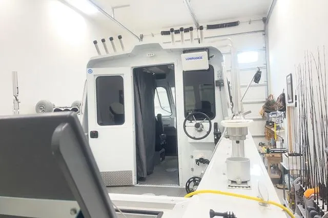 Slide: The Image of 2020 Hewescraft 240 Ocean Pro boat interior in a garage, featuring fishing equipment. - 5