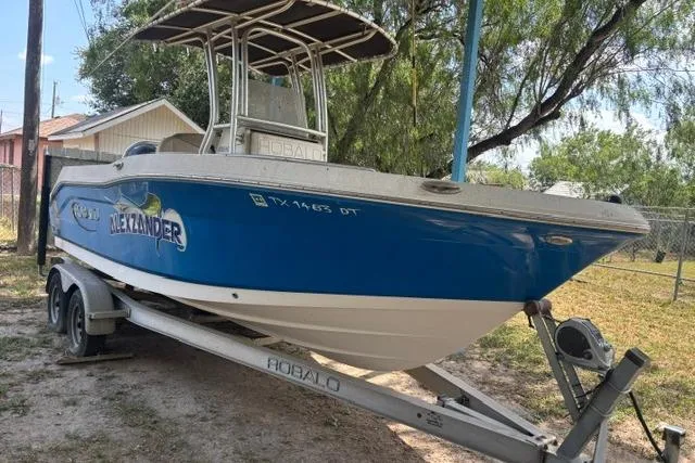 Slide: The Image of 2017 Robalo R200 Center Console boat on trailer, blue and white, parked outdoors. - 5