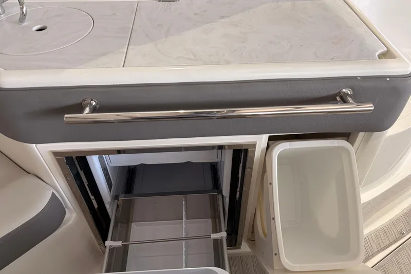 Slide: The Image of Interior of 2027 Sea Ray Sundancer 320 with open fridge and trash bin. - 14
