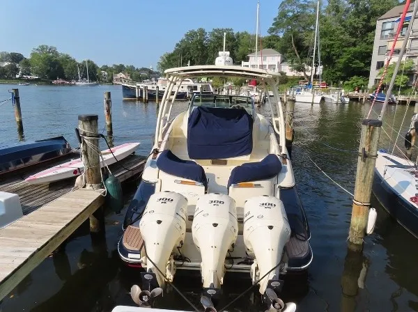 Slide: The Image of A 2016 Chris-Craft 36 Launch docked in a calm marina, featuring three outboard engines. - 2