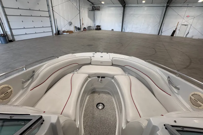 Slide: The Image of 2005 Crownline 220 EX boat interior with white seating and red accents in a spacious warehouse. - 16