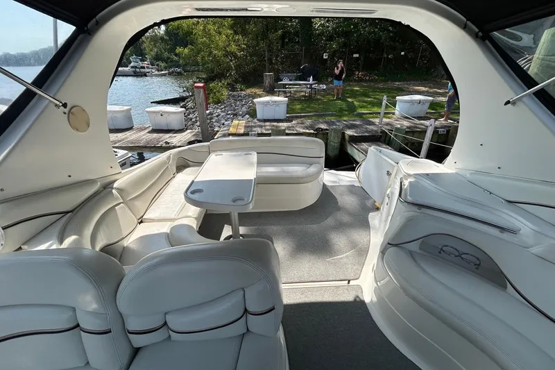 Slide: The Image of 2001 Wellcraft 3700 Martinique boat interior with white seating and table, docked by a lake. - 15