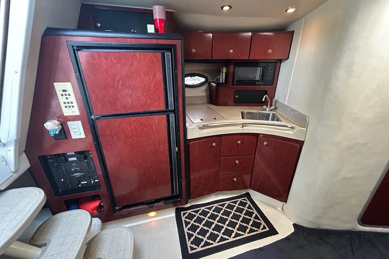Slide: The Image of 2001 Wellcraft 3700 Martinique yacht interior with kitchenette, featuring wood cabinets and modern appliances. - 22