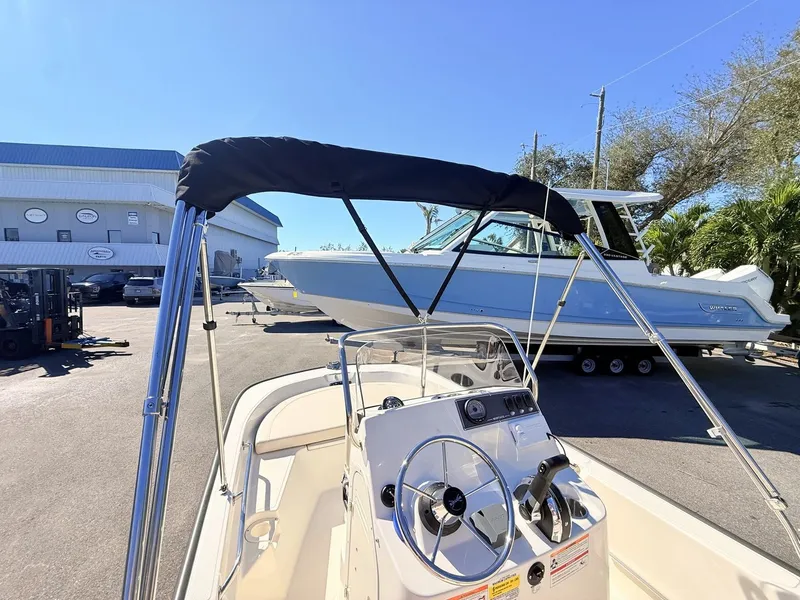 Slide: The Image of Boston Whaler 150 Montauk 2027 with a Bimini top and helm console, parked on a trailer. - 21