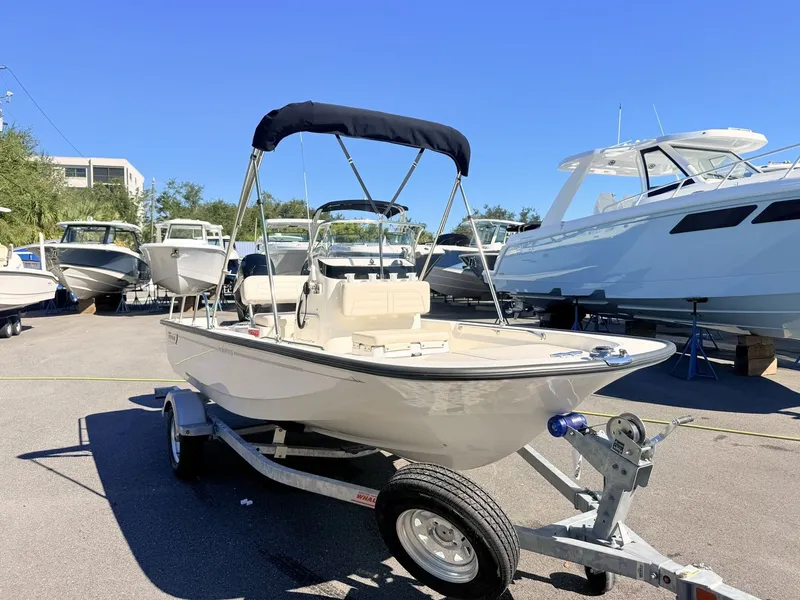 Slide: The Image of 2027 Boston Whaler 150 Montauk on a trailer, featuring a sunshade, in a marina setting. - 11