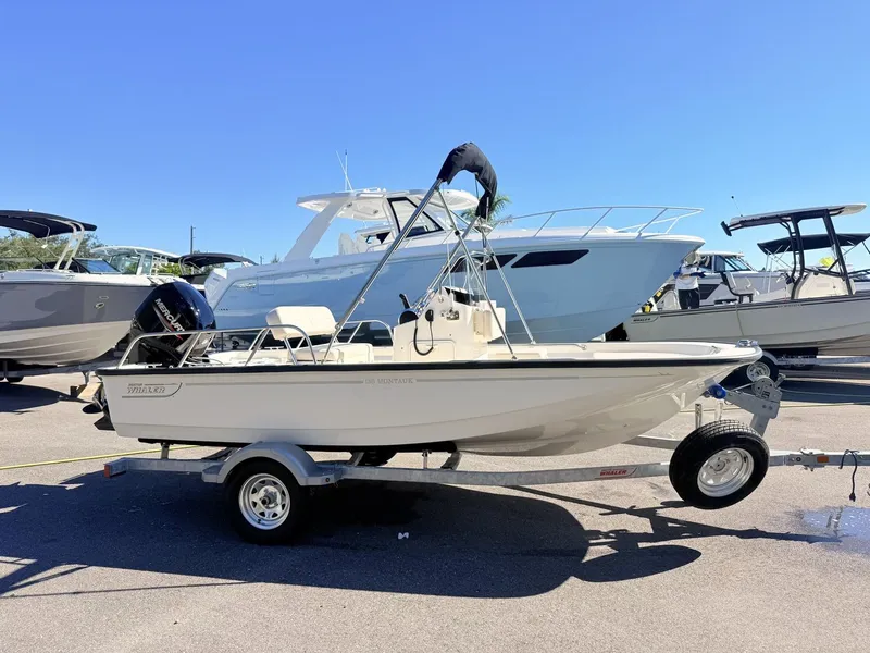 Slide: The Image of A 2027 Boston Whaler 150 Montauk on a trailer in a marina area. - 2