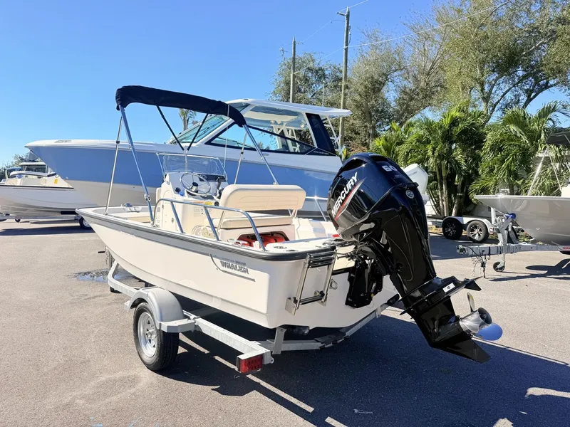 Slide: The Image of A 2027 Boston Whaler 150 Montauk on a trailer. It features a black canopy and a Mercury engine. - 6