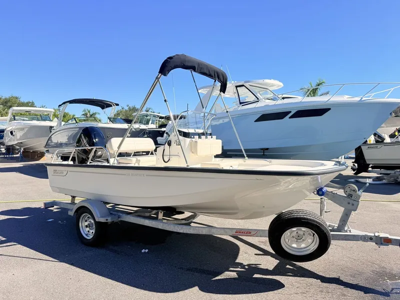 Slide: The Image of Boston Whaler 150 Montauk 2027 on a trailer, surrounded by other boats outdoors. - 12