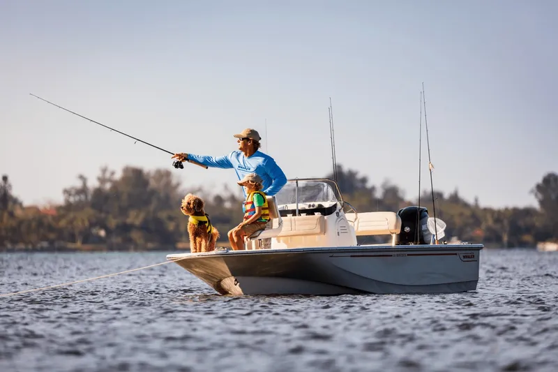 Slide: The Image of A man and child fishing on a Boston Whaler 150 Montauk with a dog on board. - 25