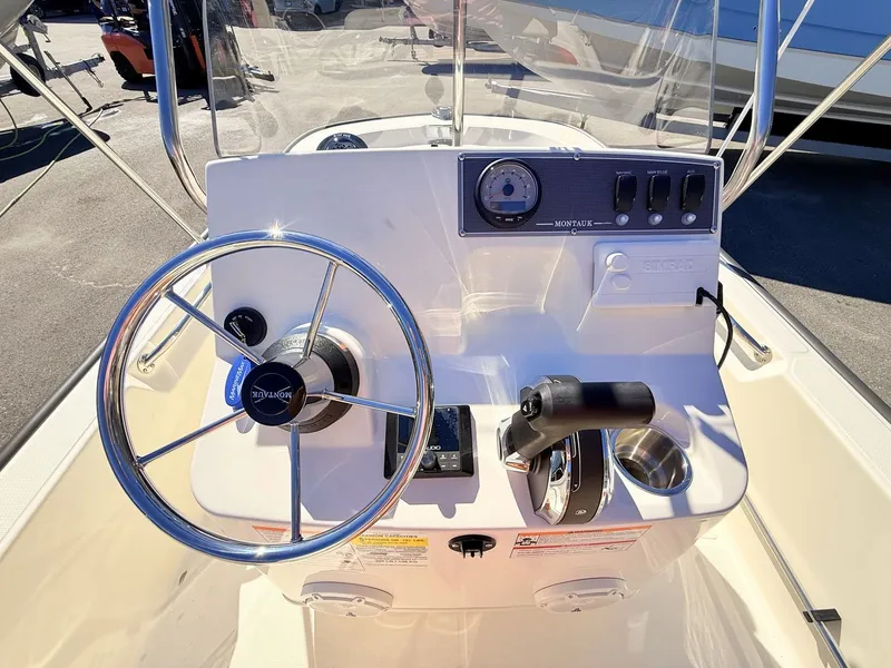 Slide: The Image of The image shows the helm of a Boston Whaler 150 Montauk boat with a steering wheel and controls. - 24