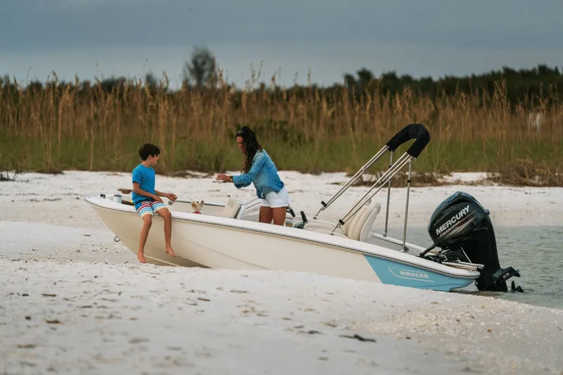 Slide: The Image of A woman and child sit on a Boston Whaler 130 Super Sport at the beach. - 7