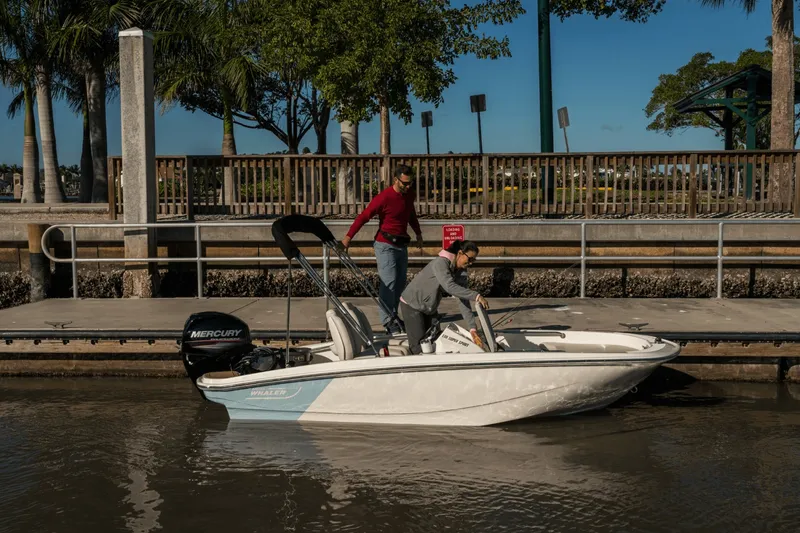 Slide: The Image of Two people on a small white boat docked, surrounded by palm trees. - 15