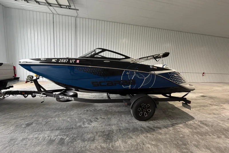 Slide: The Image of 2022 Scarab 195 ID boat in a garage, blue and black design, on a trailer. - 3