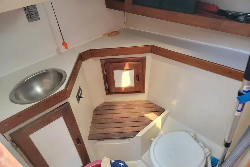 Slide: The Image of Interior of a 1986 Catalina 34 sailboat bathroom with sink, toilet, and wooden accents. - 8