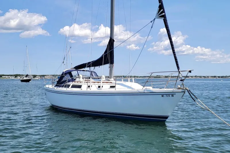 Slide: The Image of 1986 Catalina 34 sailboat anchored on calm water under a clear blue sky. - 21
