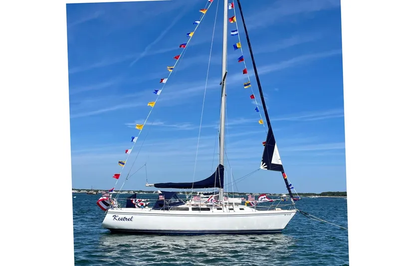 Slide: The Image of 1986 Catalina 34 MkII sailboat adorned with colorful flags on a sunny day. - 18