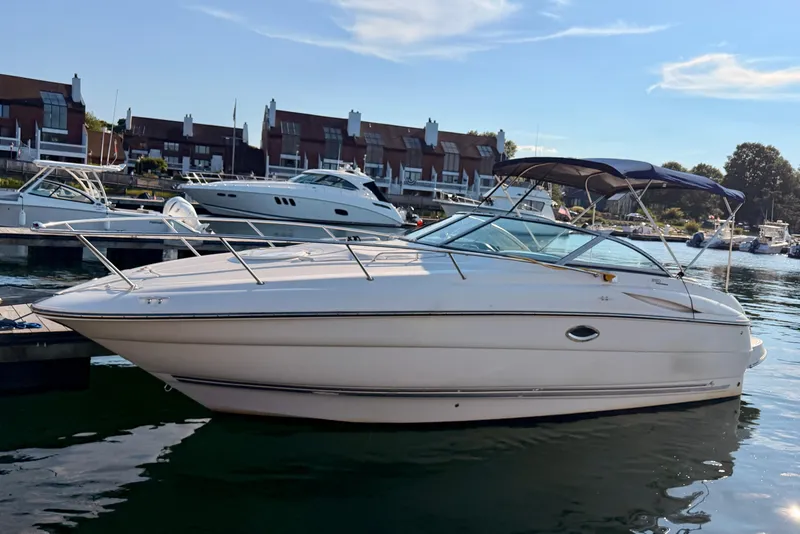 The Image of 2009 Monterey 250 Cruiser boat docked at marina with waterfront buildings in background. - 0