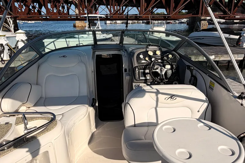 Slide: The Image of 2009 Monterey 250 Cruiser boat interior with white seating and control panel, docked by water. - 5
