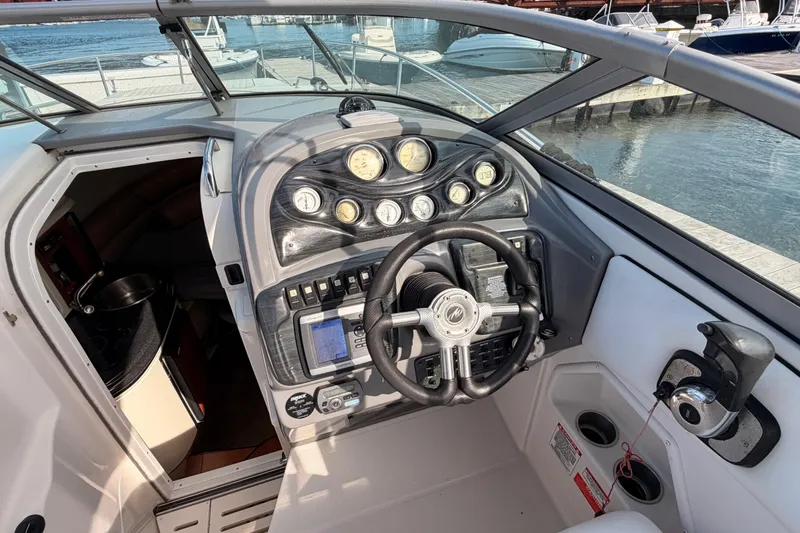 Slide: The Image of 2009 Monterey 250 Cruiser helm with gauges, steering wheel, and cabin entrance by the dock. - 6
