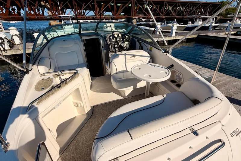 Slide: The Image of 2009 Monterey 250 Cruiser boat interior with seating, table, and helm, docked by a bridge. - 4