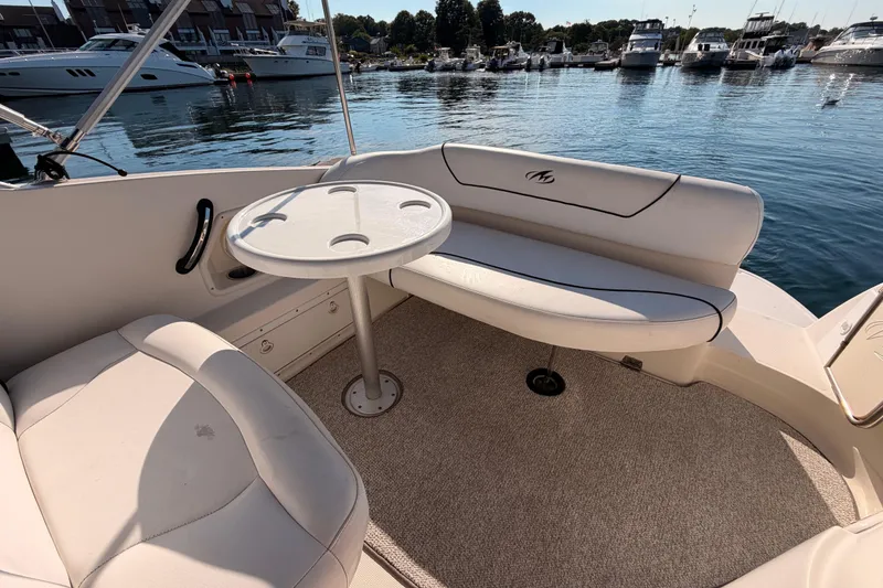 Slide: The Image of 2009 Monterey 250 Cruiser interior with seating and table, docked at a marina. - 7