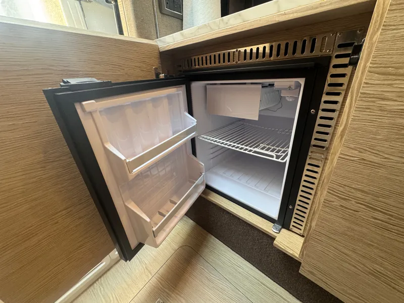 Slide: The Image of An open refrigerator in a boat cabin with wood paneling and shelving. - 33