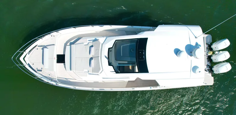 Slide: The Image of Aerial view of a white 2019 Azimut Verve 40 on calm water, featuring a spacious deck and three outboard engines. - 1