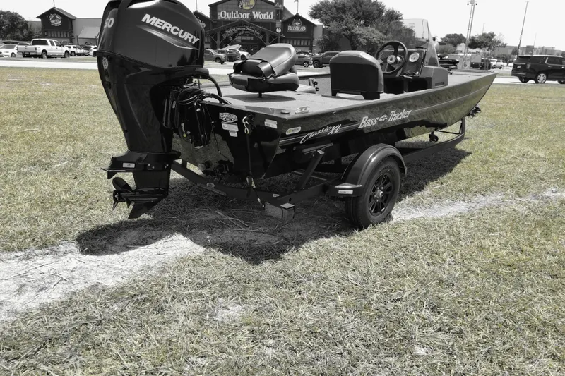 Slide: The Image of 2026 Bass Tracker boat with Mercury engine on grassy field near Outdoor World. - 4