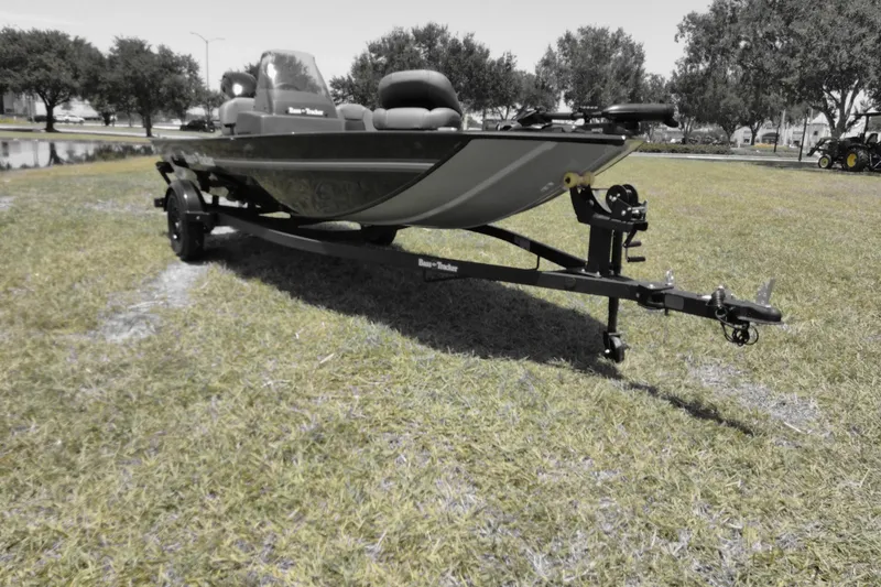 Slide: The Image of 2026 Bass Tracker boat on trailer, parked on grassy area with trees in background. - 3