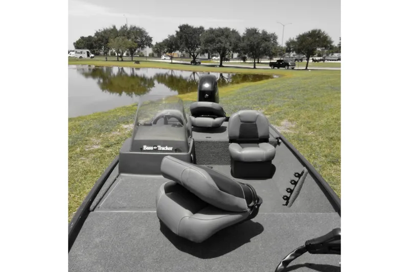 Slide: The Image of 2026 Bass Tracker boat with seating, parked near a pond, surrounded by trees and grass. - 8