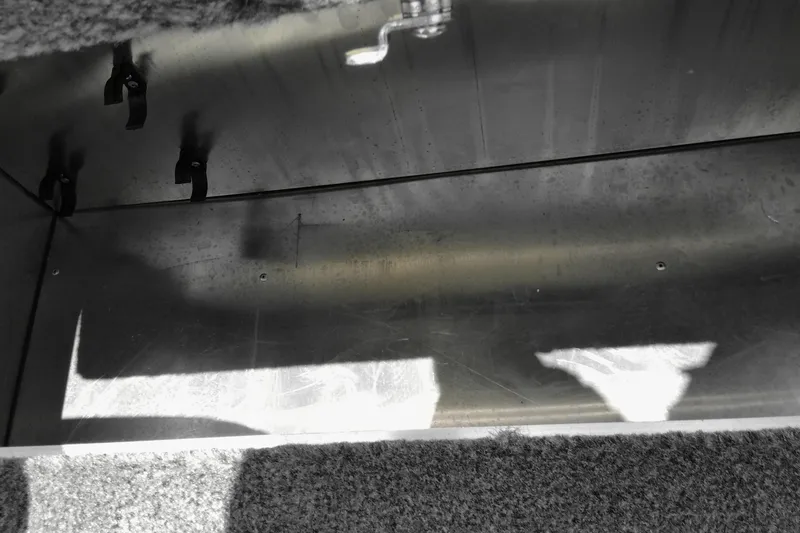 Slide: The Image of Interior view of a 2026 Bass Tracker boat compartment with hooks and carpeted edges. - 11