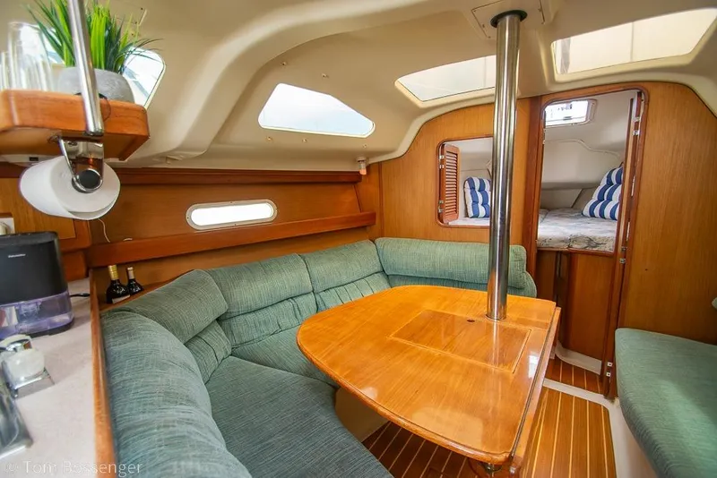 Slide: The Image of Cozy interior of 1999 Hunter 340 sailboat with wooden table and green seating. - 15