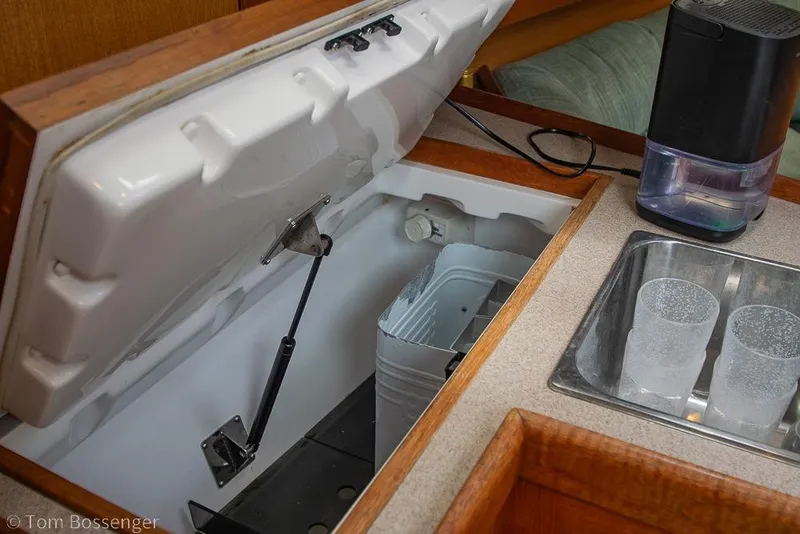 Slide: The Image of Interior of a 1999 Hunter 340 yacht showing an open fridge, sink, and water filter. - 12