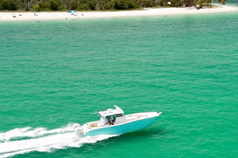 Slide: The Image of 2025 Insetta 35IFC boat cruising on turquoise waters near a sandy beach. - 1