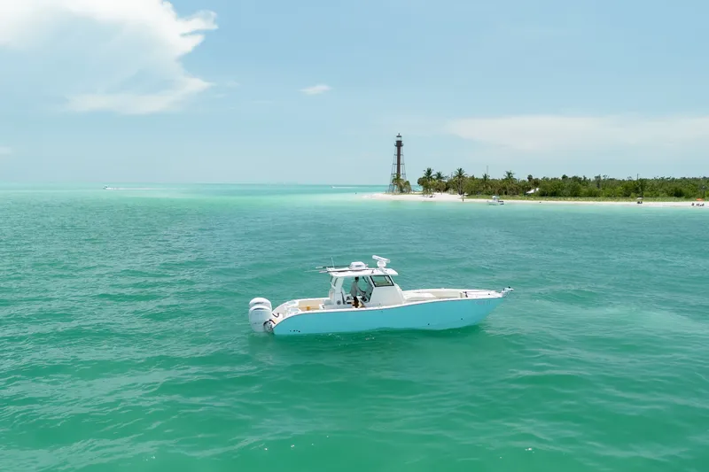 Slide: The Image of 2025 Insetta 35IFC boat cruising near a tropical island with a lighthouse. - 2