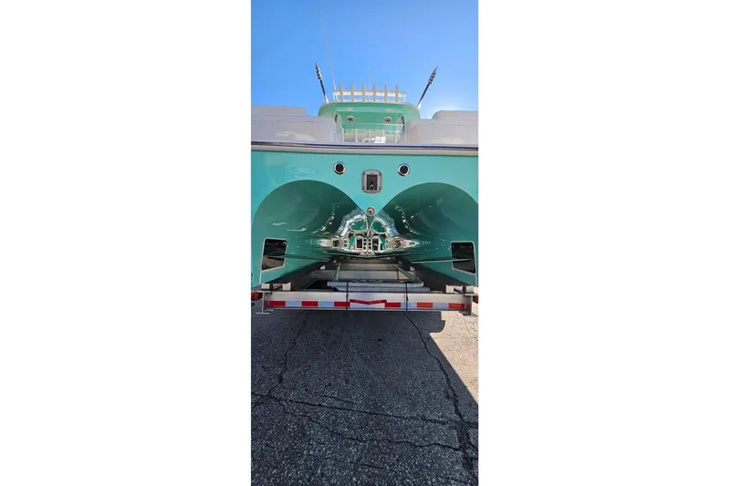 Slide: The Image of 2025 Insetta 35IFC boat on trailer, rear view, turquoise hull, sunny day. - 2