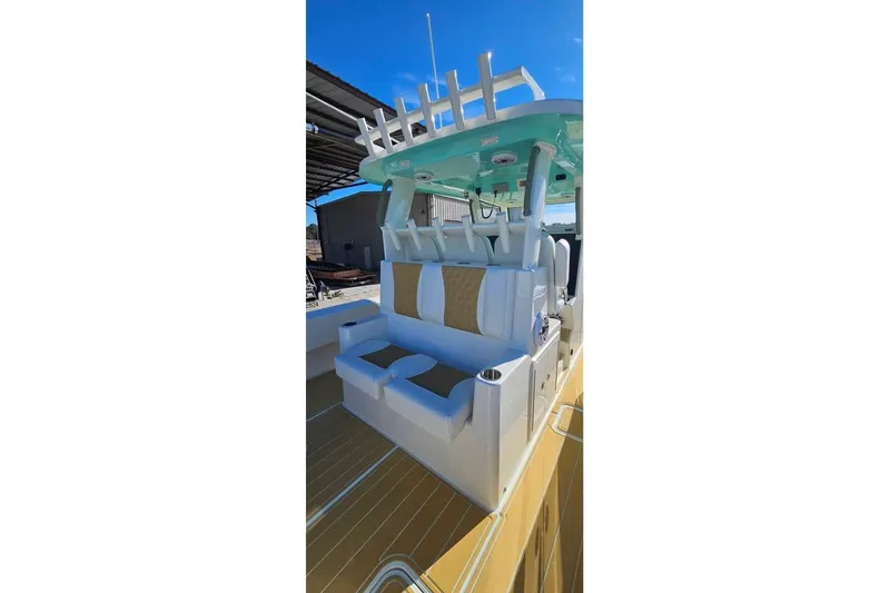 Slide: The Image of 2025 Insetta 35IFC boat interior with cushioned seating and rod holders under a clear blue sky. - 12