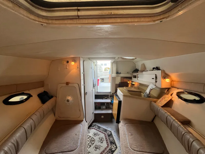 Slide: The Image of Interior of a 1998 Doral 250 SC with cozy seating and a small kitchen area. - 12