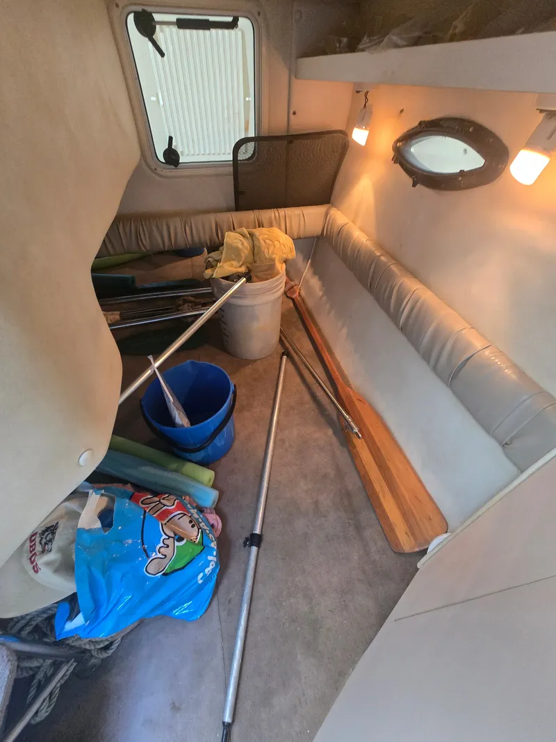 Slide: The Image of The interior of a 1998 Doral 250 SC with a bench seat, porthole, and various items. - 14