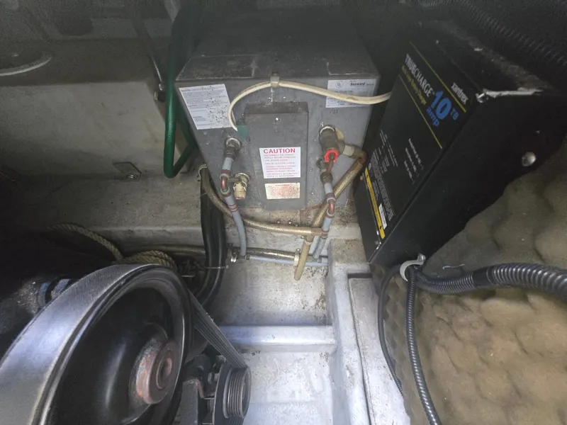 Slide: The Image of An engine compartment with various hoses and a black device. - 18