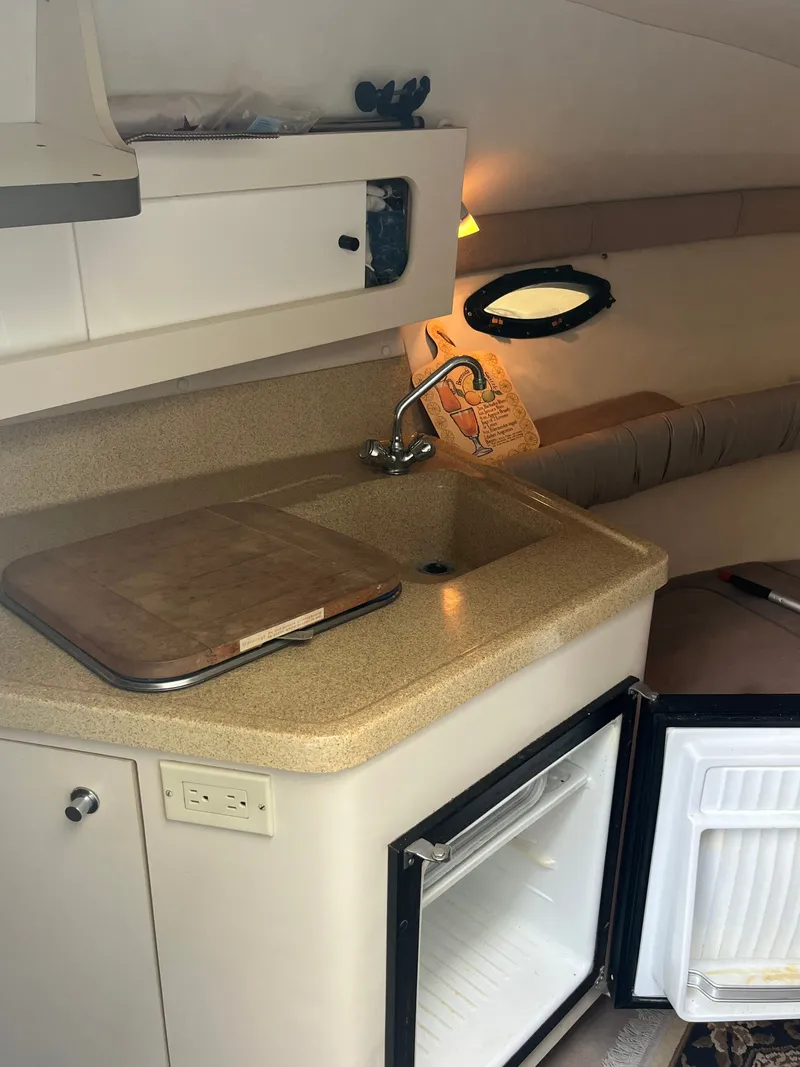 Slide: The Image of The interior of a 1998 Doral 250 SC features a small kitchenette with a sink and refrigerator. - 11