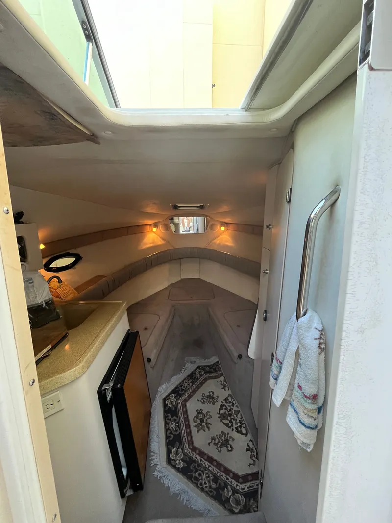 Slide: The Image of Interior of a 1998 Doral 250 SC with carpet, small kitchenette, and cozy lighting. - 10