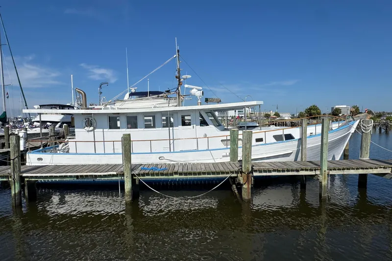 The Image of Custom 1985 Bill Holland trawler docked at a marina under clear blue skies. - 1