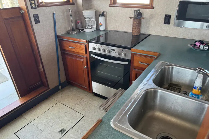 Slide: The Image of Kitchen area of a 1985 custom Bill Holland trawler with stove, sink, and wooden cabinets. - 7