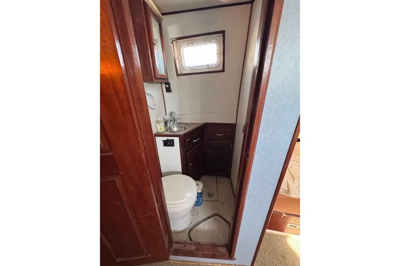 Slide: The Image of Compact bathroom in a 1985 custom Bill Holland trawler, featuring wooden cabinetry and a small sink. - 15