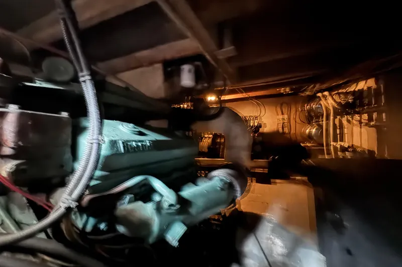 Slide: The Image of Engine room of a 1985 custom Bill Holland trawler, showcasing mechanical components and wiring. - 10