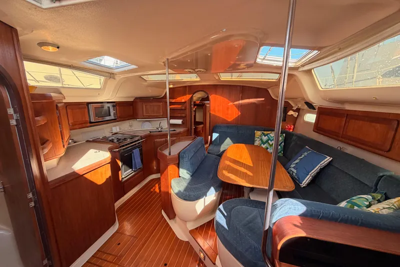 Slide: The Image of Interior of a 1997 Hunter 430 sailboat with cozy seating and a well-equipped kitchen. - 83